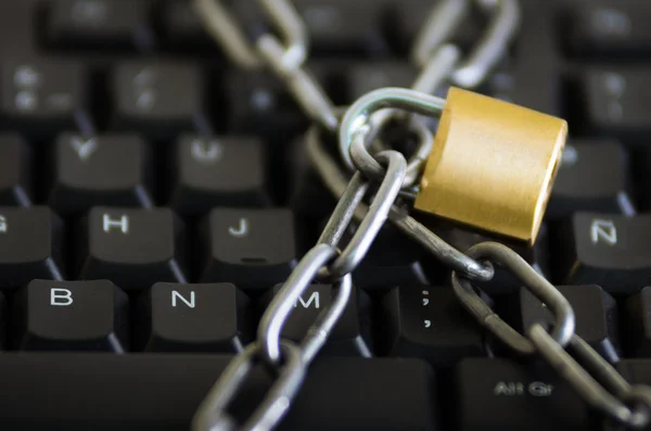 Padlock with metal chain hooked and locked across computer keyboard, internet security concept — Stock Photo, Image