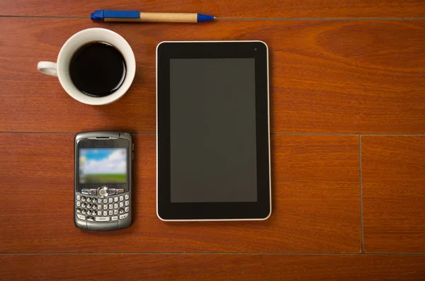 Blocco note, telefono cellulare, tablet e tazza di caffè visti dall'alto seduti su una superficie di legno — Foto Stock