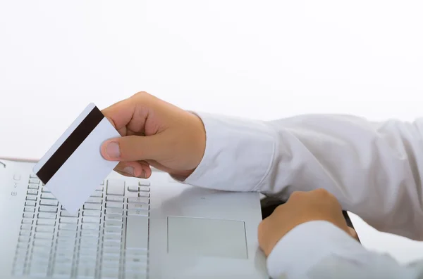 Κοντινά πλάνα άνθρωπος κρατώντας λευκή ηλεκτρονική κάρτα ολίσθησης και πιέζοντας το πληκτρολόγιο φορητού υπολογιστή — Φωτογραφία Αρχείου