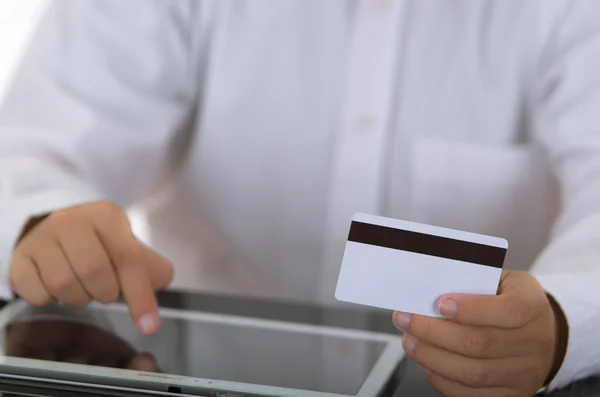 Ο άνθρωπος closeup κρατώντας λευκό ηλεκτρονικών σουφρώνω κάρτα και πιέζοντας την οθόνη του tablet — Φωτογραφία Αρχείου