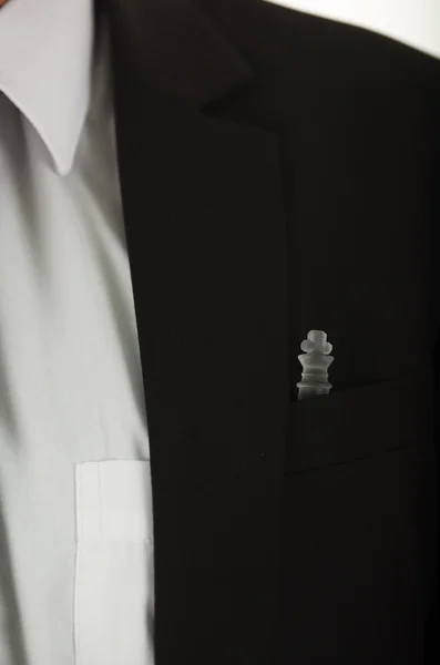 Closeup black suit jacket chest pocket with glass chess piece sitting inside, white shirt and tie visible — Stock Photo, Image