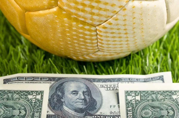 Fußball auf Rasenfläche mit herumliegenden Dollarscheinen, Wettkonzept — Stockfoto