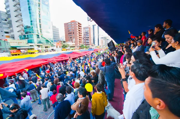Quito, Équateur - 7 avril 2016 : Un groupe de personnes arborant un très grand drapeau équatorien, des pancartes de protestation et des journalistes lors de manifestations anti-gouvernementales sur l'avenue Shyris . — Photo