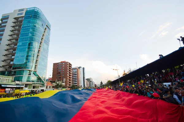 Quito, Ecuador - 7 de abril de 2016: Grupo de personas mostrando una gran bandera ecuatoriana, pancartas de protesta y periodistas durante protestas contra el gobierno en la Avenida Shyris . — Foto de Stock
