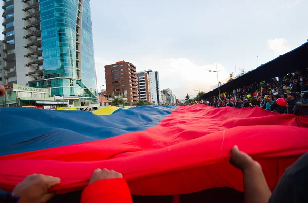 Quito, Équateur - 7 avril 2016 : Un groupe de personnes arborant un très grand drapeau équatorien, des pancartes de protestation et des journalistes lors de manifestations anti-gouvernementales sur l'avenue Shyris . — Photo