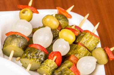 Turşu, zeytin, beyaz tabağında, ahşap yüzey arka plan yukarıda da görüleceği gibi yalan capiscum ve bebek soğan sebze şişleri