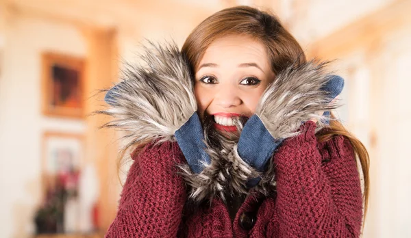 Pretty young brunette woman squeezing her head between large blue scarf and smiling, freezing cold concept — Stock Photo, Image