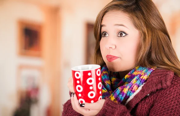 Mooie jonge brunette vrouw dragen rode jas en sjaal, met kopje warme drank — Stockfoto