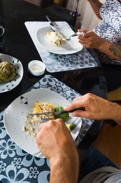 Crepe ricoperto di salsa bianca sdraiato sul piatto con pezzi di broccoli, l'uomo mangia come visto dall'alto, apparecchiare la tavola di classe — Foto Stock