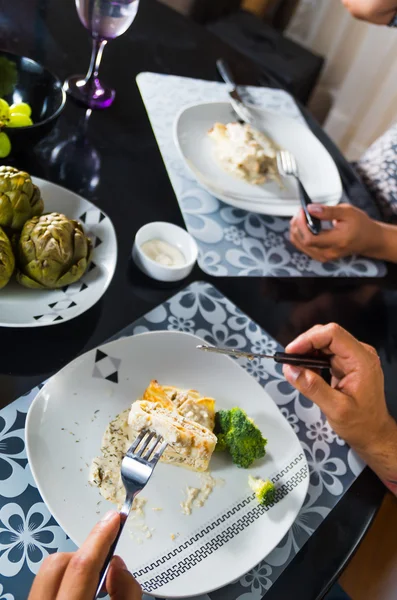 Crepe ricoperto di salsa bianca sdraiato sul piatto con pezzi di broccoli, l'uomo mangia come visto dall'alto, apparecchiare la tavola di classe — Foto Stock