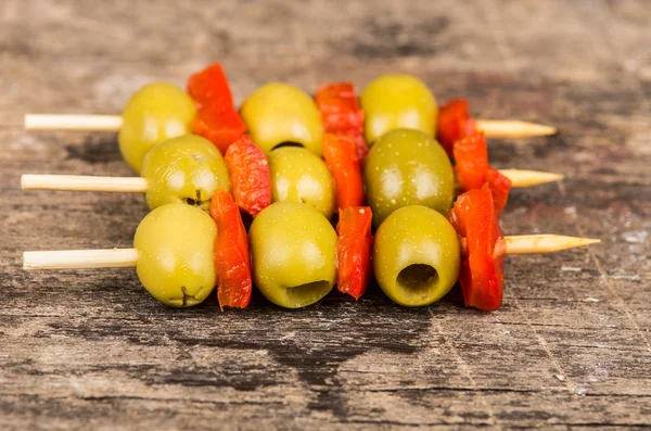 Vegetable skewers of olives and capiscum lying on grey stone surface as seen from above — Stock Photo, Image