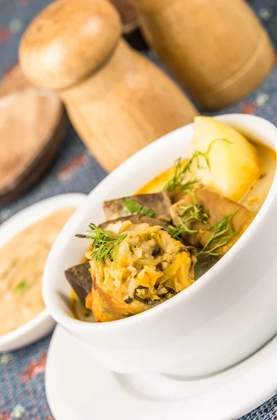 Classy serving of potato soup with meat and vegatables, served in white bowls sitting on table, blue tablecloth, salt pepper shakers, cozy restaurant background — Stock Photo, Image