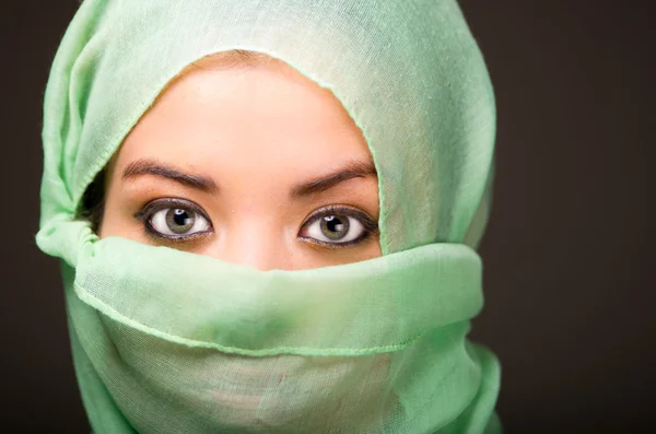 Vrouw dragen turkooizen sjaal voor gezicht alleen onthullen mooie groene ogen, grijze donkere achtergrond — Stockfoto