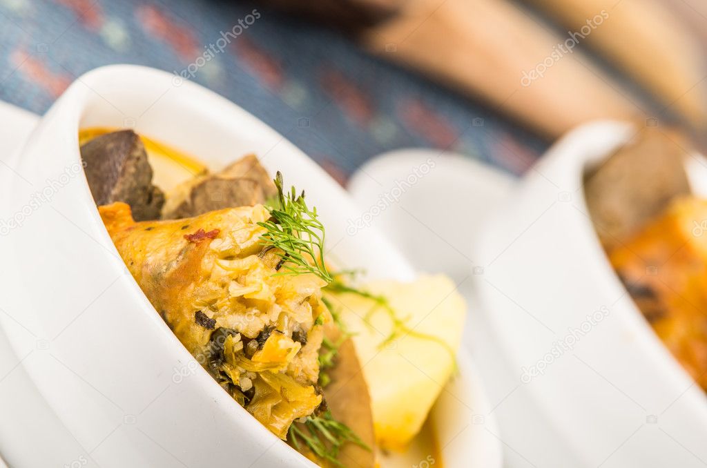 Classy serving of potato soup with meat and vegatables, served in white bowls sitting on table, blue tablecloth, cozy restaurant background