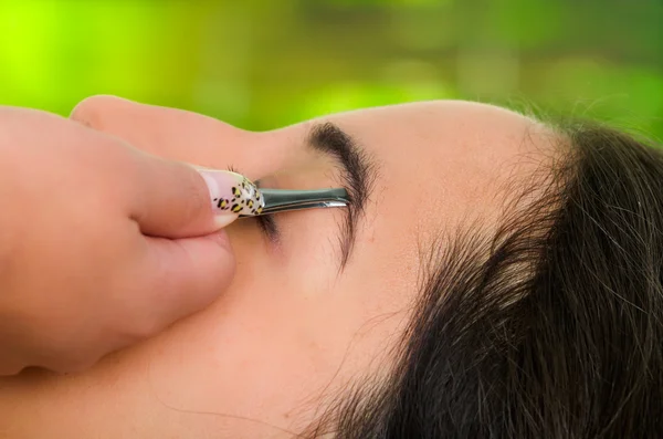 Closeup woman headshot profile,lying with eyes closed and hand holding tweezer pulling eyebrow — Stock Photo, Image