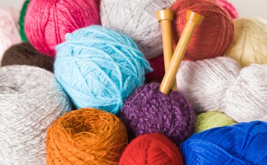 Portre renkli iplik topları, beyaz, mavi, pembe, mor, kahverengi ahşap örgü iğneleri orta ile yığını
