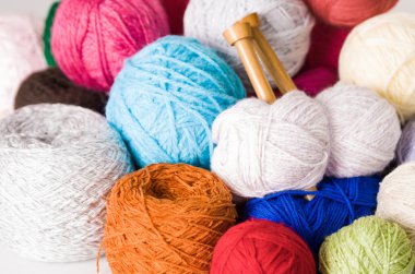 Portre renkli iplik topları, beyaz, mavi, pembe, mor, kahverengi ahşap örgü iğneleri orta ile yığını