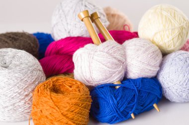 Portre renkli iplik topları, beyaz, mavi, pembe, mor, kahverengi ahşap örgü iğneleri orta ile yığını