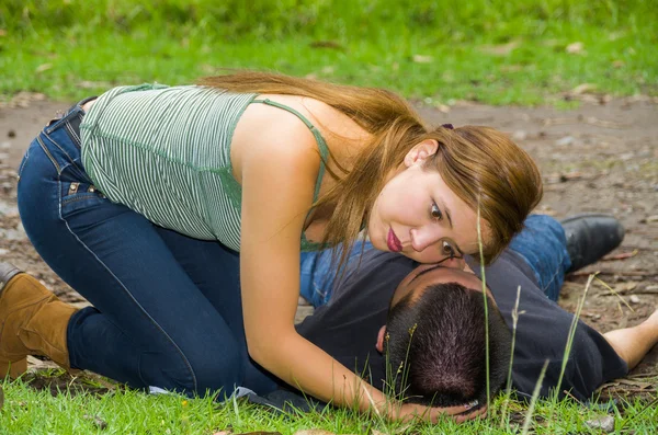 Hombre joven acostado con emergencia médica, mujer sentada a su lado buscando aliento, ambiente al aire libre —  Fotos de Stock