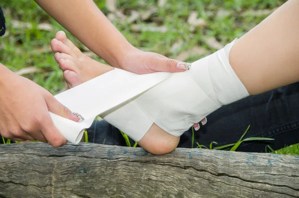 Closeup females injured ankle, getting bandage compression wrap — Stock Photo, Image