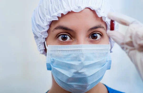 Krankenschwester mit Bouffant-Mütze und Gesichtsmaske, die braune Pillenkapsel für die Kamera hochhält, grauer Hintergrund. — Stockfoto