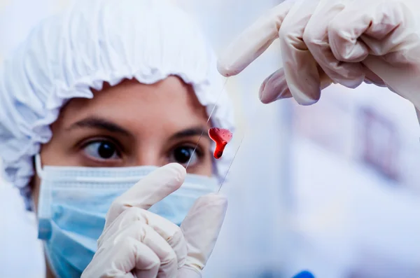 Closeup headshot νοσοκόμα φορώντας σχημάτιζε μπουφάν κάλυμμα και μάσκα προσώπου που κρατά ψηλά το δείγμα αίματος σε διαφάνεια γυαλί για τη φωτογραφική μηχανή — Φωτογραφία Αρχείου
