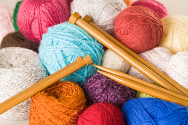 Fechar pilha de bolas de fios coloridos, branco, azul, rosa, roxo e marrom com agulhas de tricô de madeira no meio — Fotografia de Stock