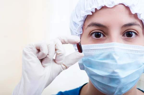 Nahaufnahme Kopfschuss Krankenschwester mit Bouffantmütze und Gesichtsmaske, die zwei Tablettenkapseln für die Kamera hochhält Stockbild