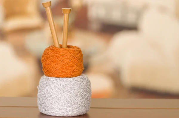 White and brown yarn balls stacked on top of each other with wooden knitting needles standing up from inside middle — Stock Photo, Image