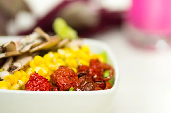 Primo piano delicata presentazione fresca di insalata in ciotola bianca con verdure colorate come funghi, mais e pomodori secchi — Foto Stock