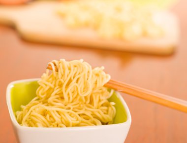 Ahşap yüzey üzerinde oturan küçük kare kase içinde pişmiş makarna zarif sunum sopa yiyecek, bulanık arka plan kapma