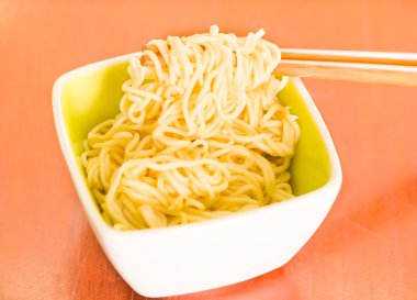 Ahşap yüzey üzerinde oturan küçük kare kase içinde pişmiş makarna zarif sunum sopa yiyecek, bulanık arka plan kapma