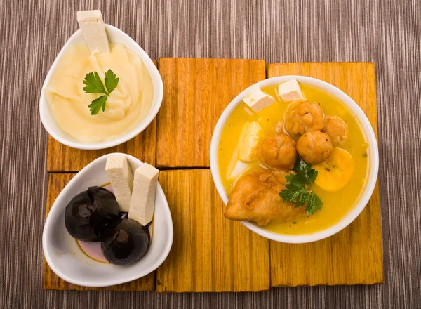 Traditional fanesca serving sitting on wooden surface with accessories next to it such as molo mashed potatoes and fig dessert — Stock Photo, Image