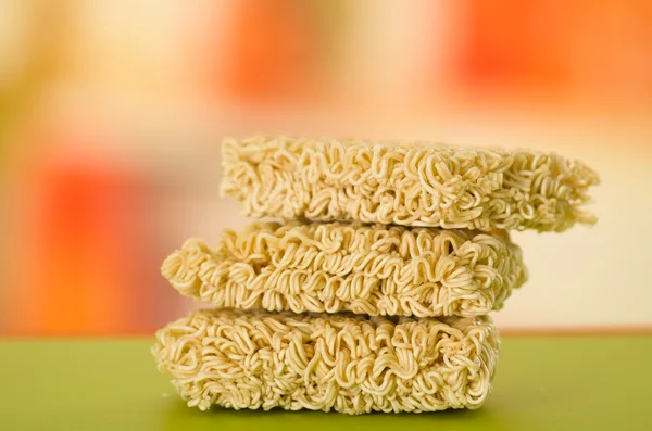 Noodles square blocks stacked on top of each other, green surface and blurry background