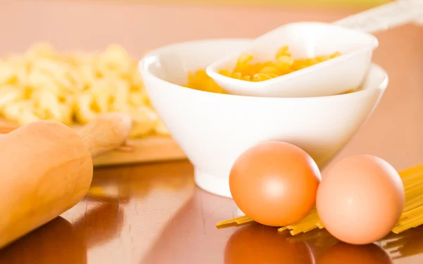 Mattarello, uova, pasta e pasta sparsi su una superficie di legno — Foto Stock