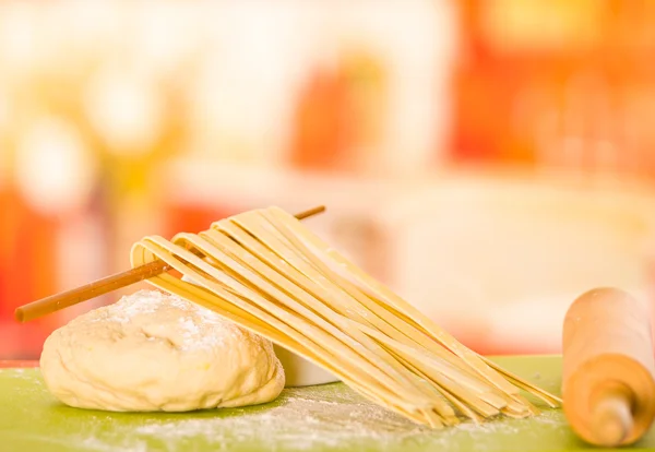 Spaghetti secchi appena fatti appesi su un bastoncino di legno appoggiato sulla pasta accanto al perno — Foto Stock