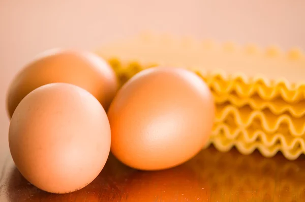 Placas de lasaña con patrón en forma de ola apiladas una sobre la otra junto a los huevos —  Fotos de Stock