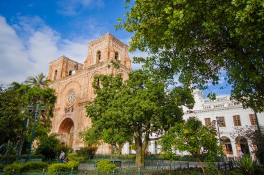 Cuenca, Ekvator - 22 Nisan 2015: yeşil ağaçlar görünür ile park arasında görüldüğü gibi şehir, güzel tuğla Mimarlık ve cephe kalbinde yer alan muhteşem ana Katedrali