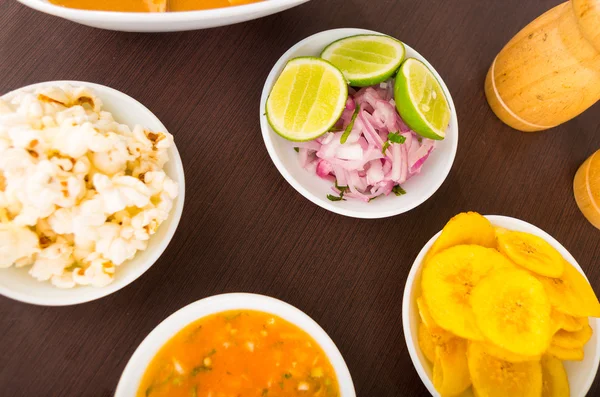 Side food for ceviche, ecuadorian style to eat. Fried bananas, pop corn, onions and lemon — Stock Photo, Image