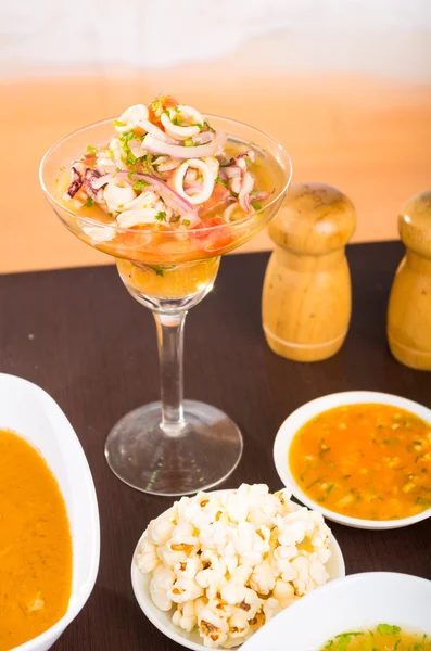 Squid and octopus delicious ceviche served on a glass cup, behind salt and pepper to prepare it — Stock Photo, Image