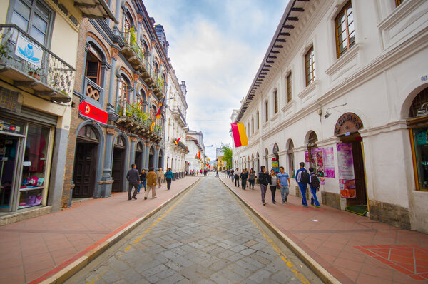 Cuenca, Ecuador - April 22, 2015: Very charming typical city street, red trowalks, narrow road in middle, beautiful buildings and shops on both sides
