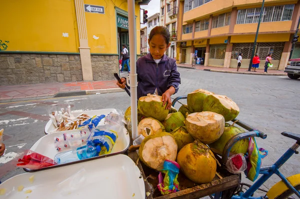 Cuenca, Ecuador - 22 April 2015: Ung tonårsflicka arbetar på kokos cykelaffär i centrum, hålla kniven använder den för att arbeta — Stockfoto