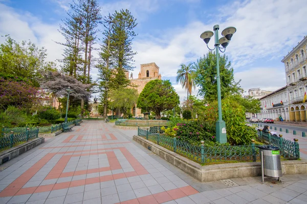 Cuenca, Ecuador - April 22, 2015: Spectacular main cathedral located in the heart of city, beautiful brick architecture and facade as seen from across park with green trees visible — Stock Photo, Image