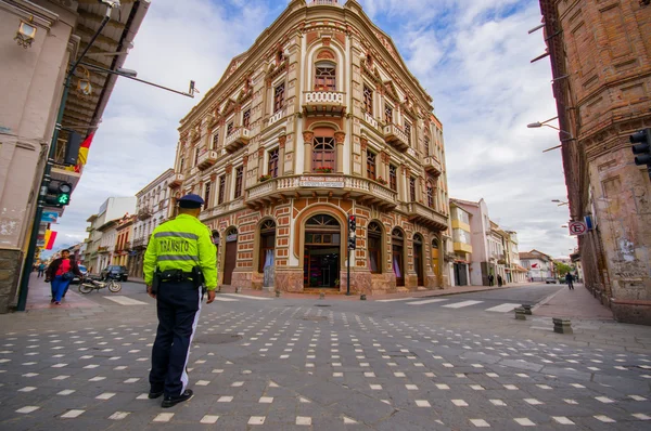 Cuenca, Ekwador - 22 kwietnia 2015: Spektakularne rogu kamienicy z tradycyjnej hiszpańskiej architektury kolonialnej, piękne detale i dekoracje, policjant widoczne z przodu kierowania ruchem — Zdjęcie stockowe