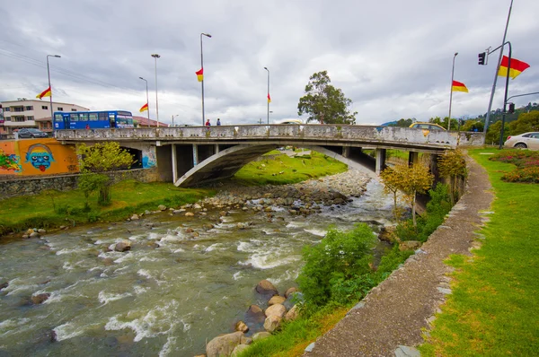 Cuenca, Ecuador - April 22, 2015: Tomebamba river as seen running through Cuenca city, peaceful and green sorroundings with bridge crossing over water — Stock Photo, Image