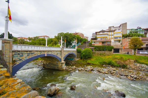 Cuenca, Ecuador - April 22, 2015: Tomebamba river as seen running through Cuenca city, peaceful and green sorroundings with bridge crossing over water — Stock Photo, Image