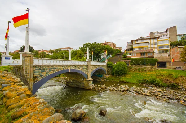 Cuenca, Ecuador - April 22, 2015: Tomebamba river as seen running through Cuenca city, peaceful and green sorroundings with bridge crossing over water — Stock Photo, Image