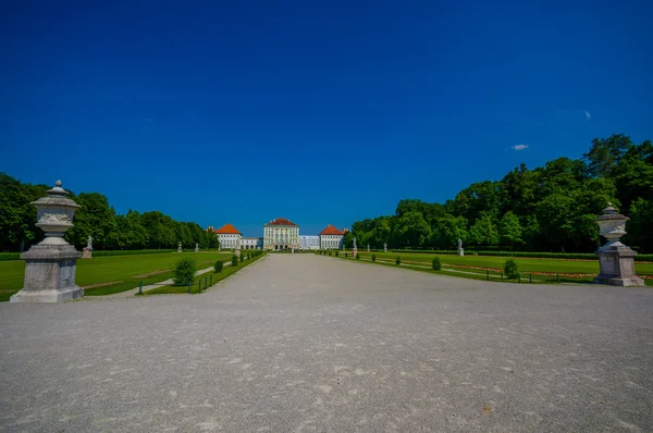 Nymphenburg, deutschland - 30. juli 2015: wunderschöner palast aus der ferne mit statuen auf beiden seiten der allee, die zum gebäude führt — Stockfoto