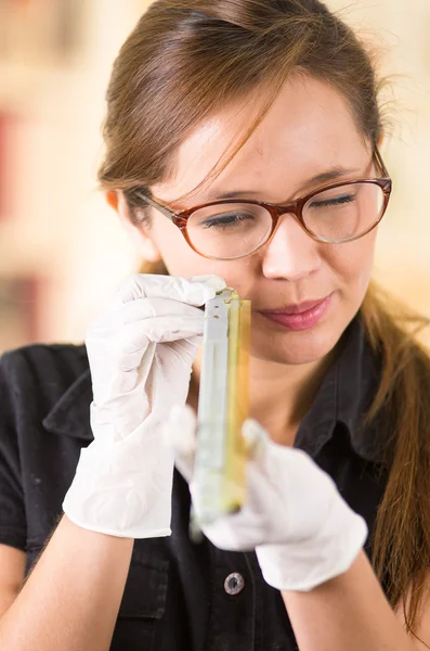 Young woman wearing black shirt holding up toner parts and looking closely into it while performing maintenance, concentrated facial expressions — Stock Photo, Image