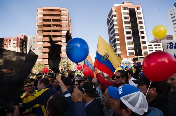 Quito, Ecuador - April 7, 2016: Group of people Holding protest signs, balloons with police and journalists during anti government protests in Shyris Avenue